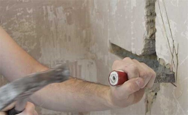 Shtroblenie väggen med en hammare och mejsel